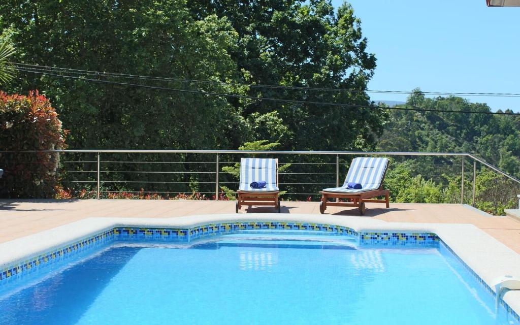 two chairs sitting next to a swimming pool at Exclusiva casa con piscina en Gondomar in Gondomar