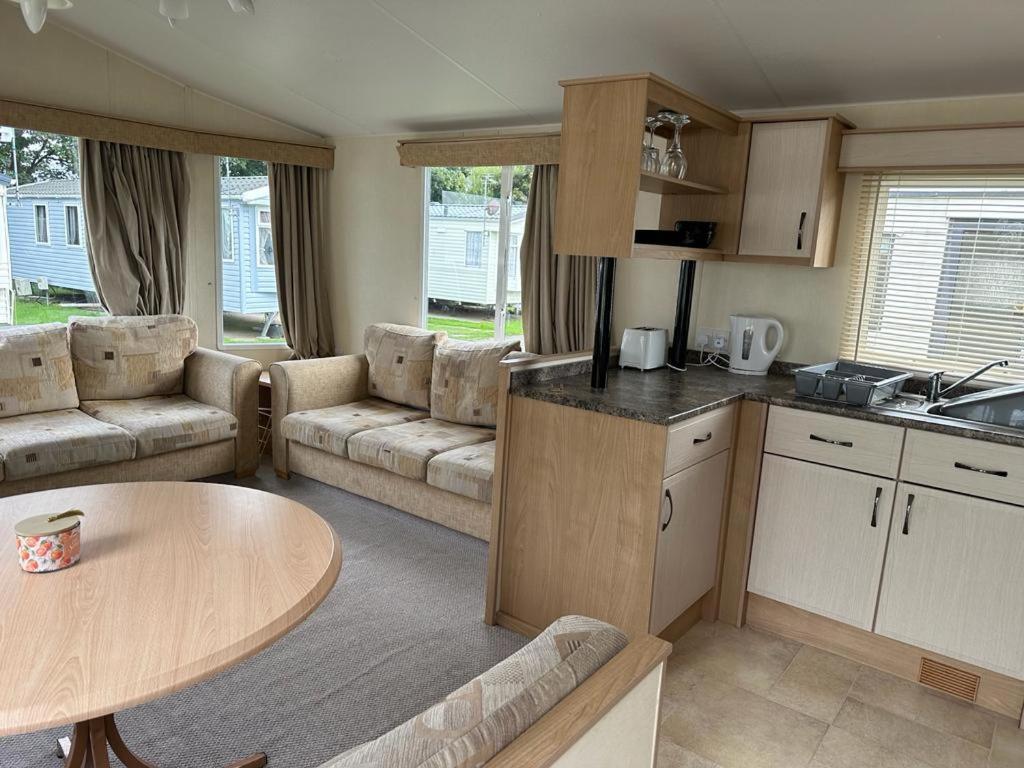 a kitchen and living room with a table and a couch at Private holiday home on Lyons Winkups holiday park, North Wales. in Kinmel Bay