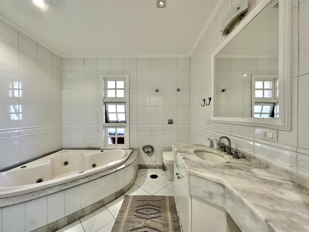 a white bathroom with a tub and a sink at Luna Hotel Boutique - Beira Mar in Guarujá