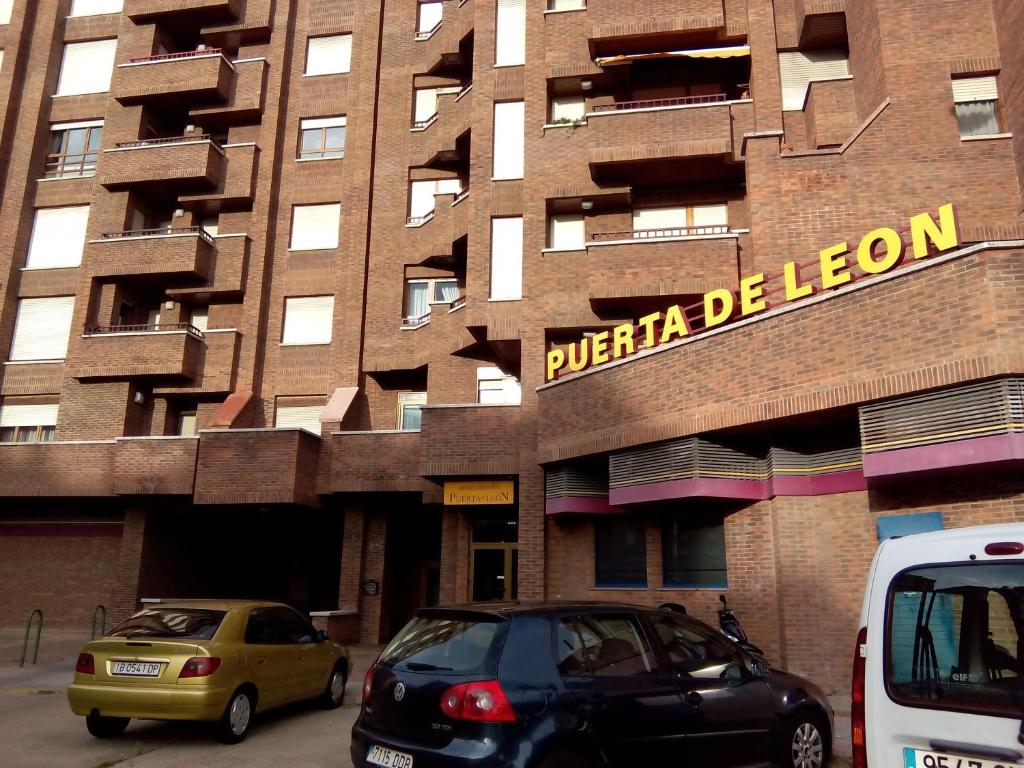 deux voitures garées devant un bâtiment dans l'établissement Apartamentos Turisticos Puerta de León, à León