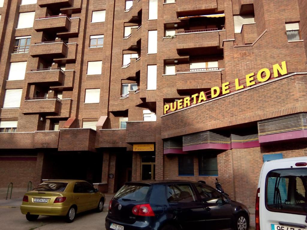 dos coches estacionados frente a un edificio en Apartamentos Turisticos Puerta de León, en León