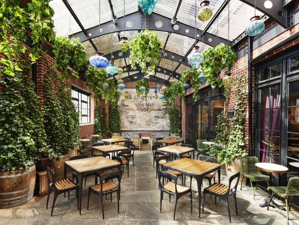 a restaurant with tables and chairs and plants at The Ludlow Hotel in New York