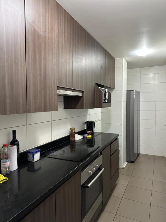 a kitchen with a black counter top and a refrigerator at Departamento Playa Brava Iquique 3D 2B in Iquique