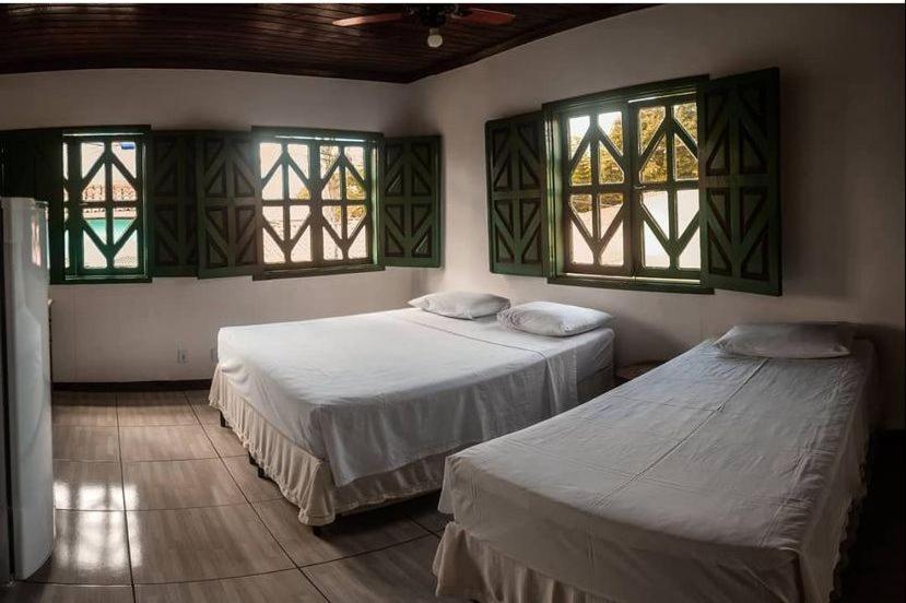 two beds in a room with windows at Pousada da Rita in Lençóis