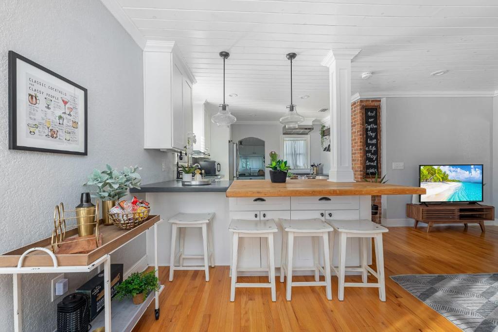 una cocina con armarios blancos y una barra con taburetes en Tiny Home - 3 MI to Downtown & Winter Park en Orlando