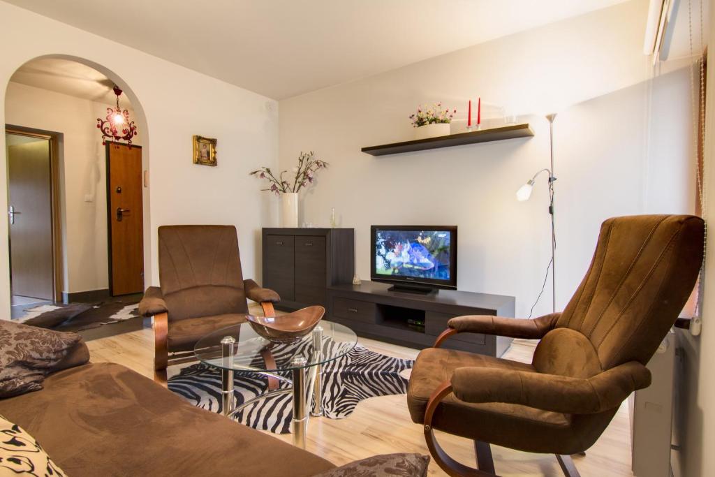 a living room with two chairs and a couch and a tv at Apartament Storczyk Zakopane in Zakopane