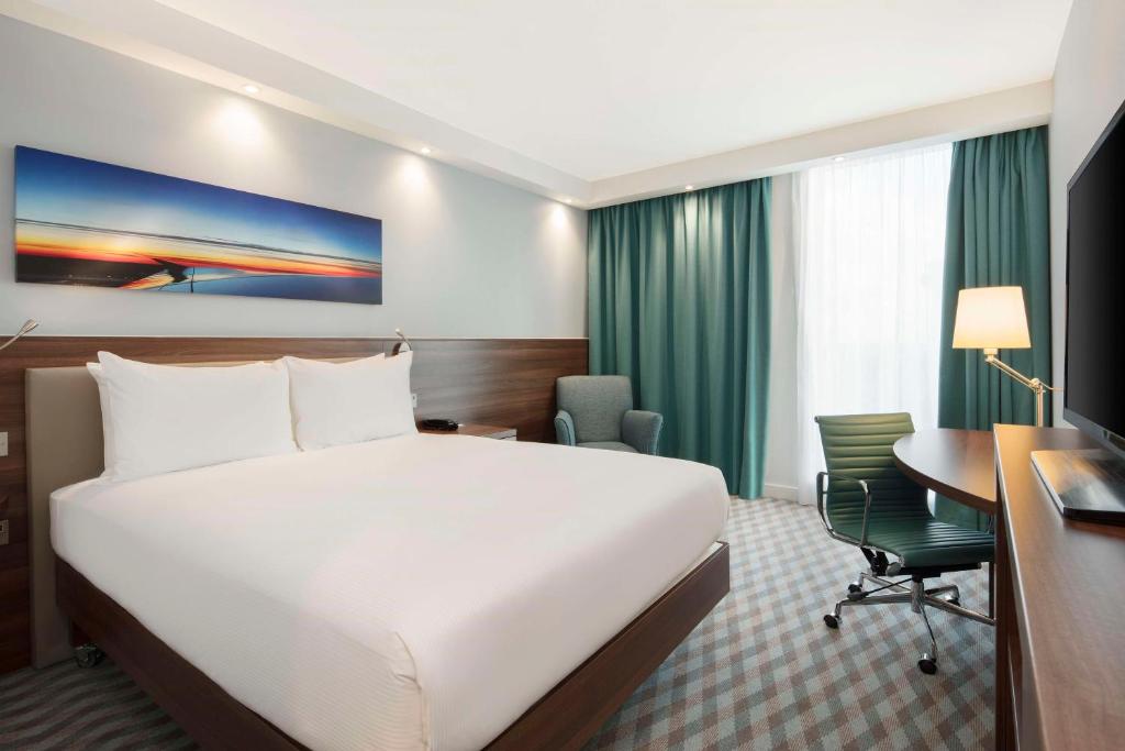 a hotel room with a bed and a desk at Hampton By Hilton London Stansted Airport in Stansted Mountfitchet