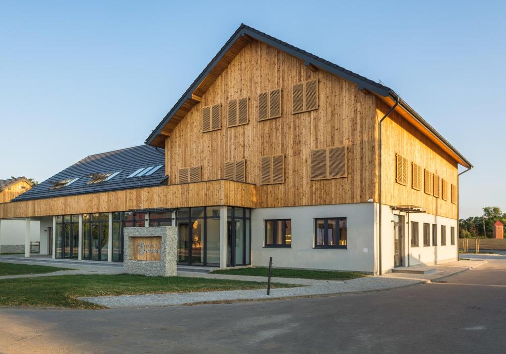 a large wooden building with a gambrel roof at Hotel Naturum in Milicz