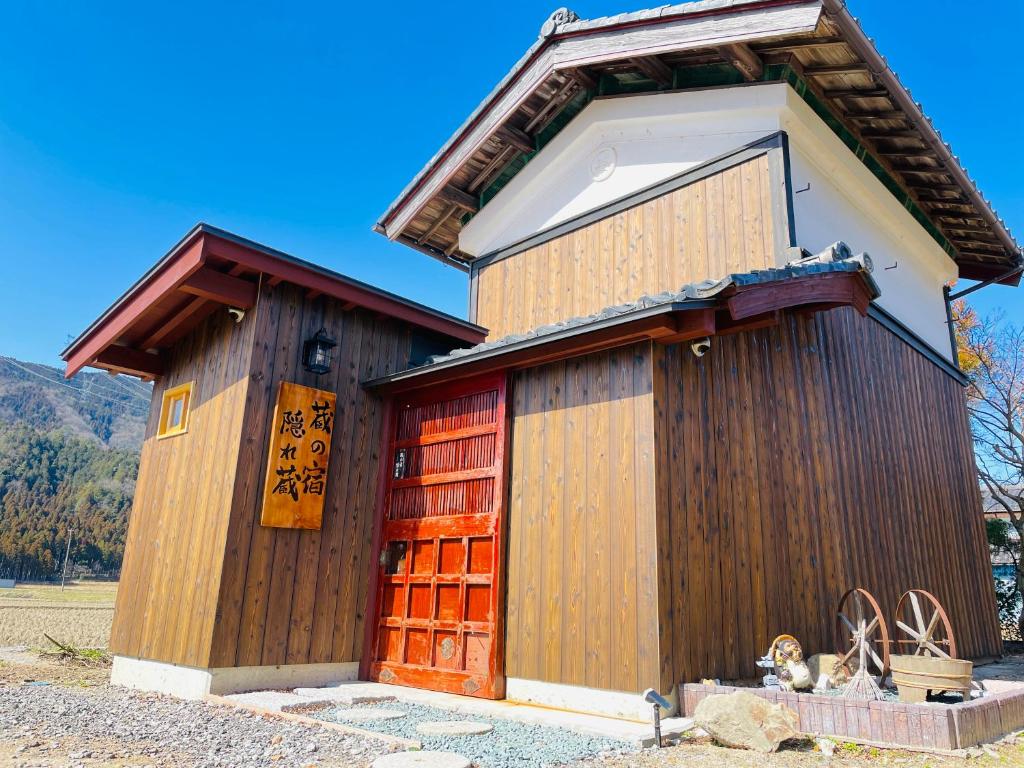 mały drewniany budynek z czerwonymi drzwiami w obiekcie 1日1組限定 1棟貸切の古民家 蔵の宿 隠れ蔵 w mieście Nagahama