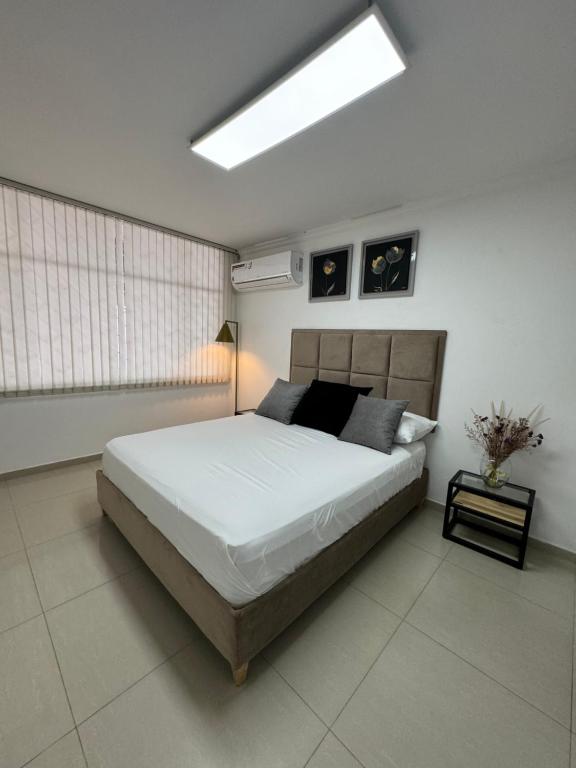 um quarto com uma grande cama branca e uma clarabóia em Apto estudio con parqueadero y wifi. em Yopal
