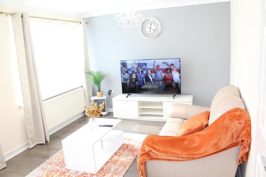 a living room with a white couch and a tv at Exquisite Stays Free parking, fast WiFi, close to city centre in Kenton