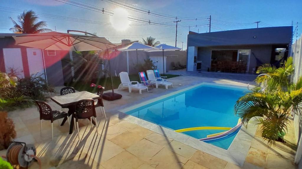 een zwembad met een tafel en stoelen naast een huis bij Casa Barramar Temporada 1 in Barra de São Miguel