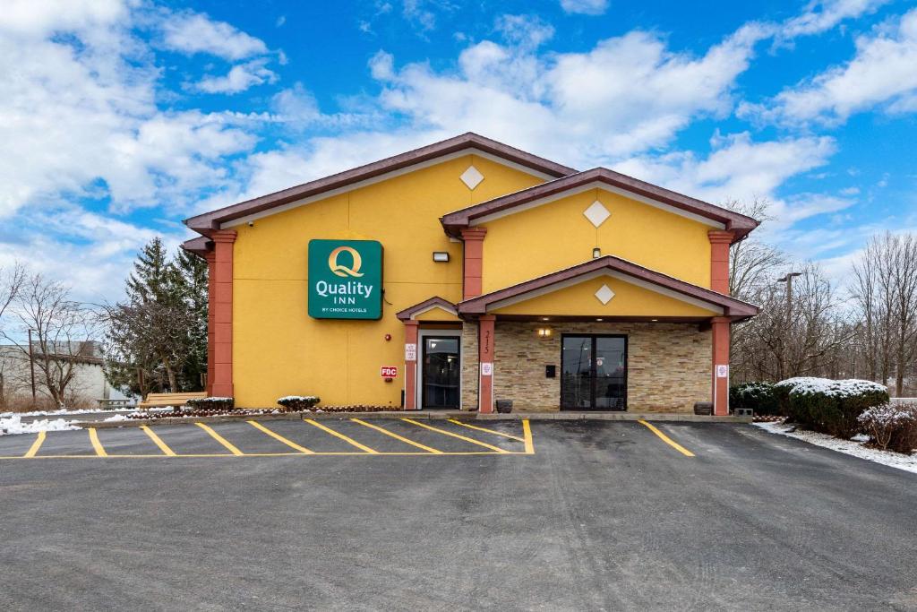 a yellow building with a sign in a parking lot at Quality Inn in Oneida