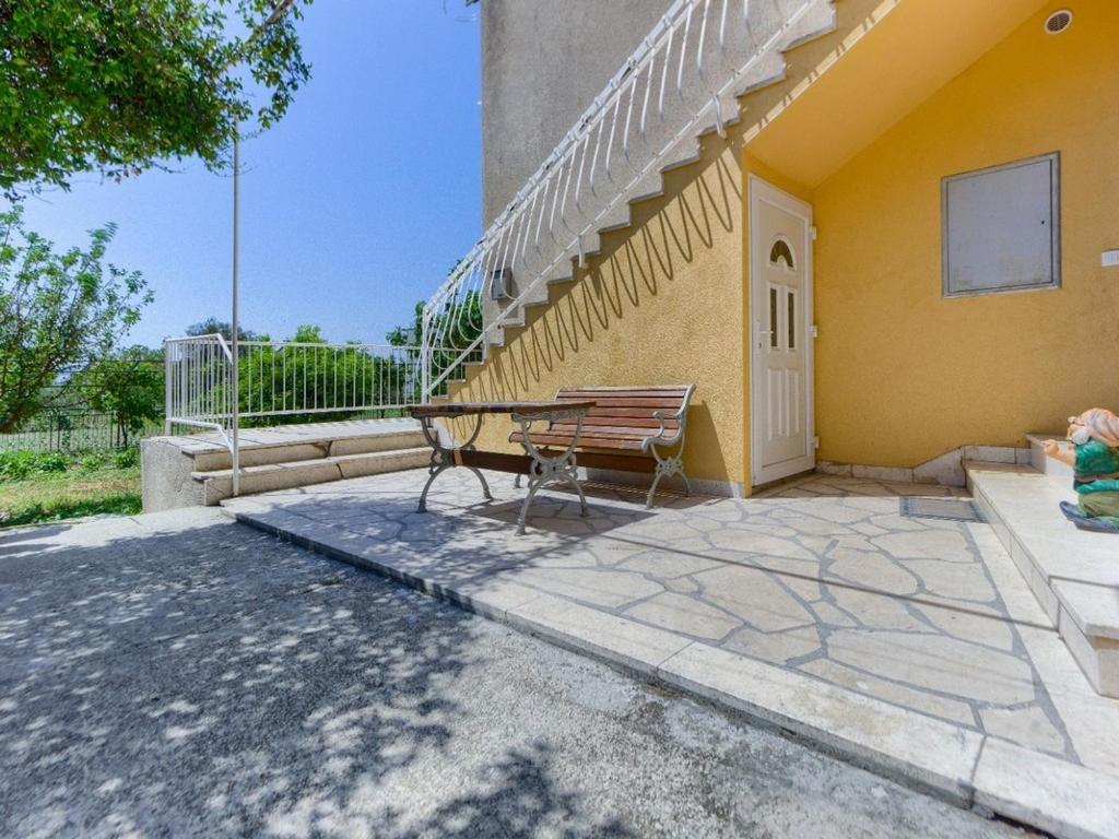 un banc assis à l'extérieur d'un bâtiment jaune dans l'établissement Apartments with a parking space Kastel Stari, Kastela - 22588, à Kaštela