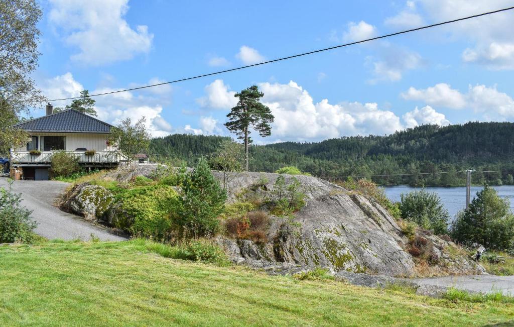a house on a hill next to a large rock at Beach Front Apartment In Øyslebø in Marnardal