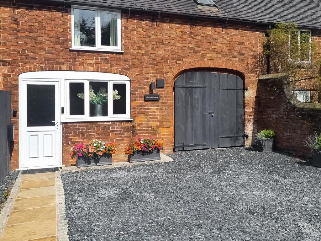 a brick house with a door and flowers in front of it at Wheelwrights Cottage in Yeaveley