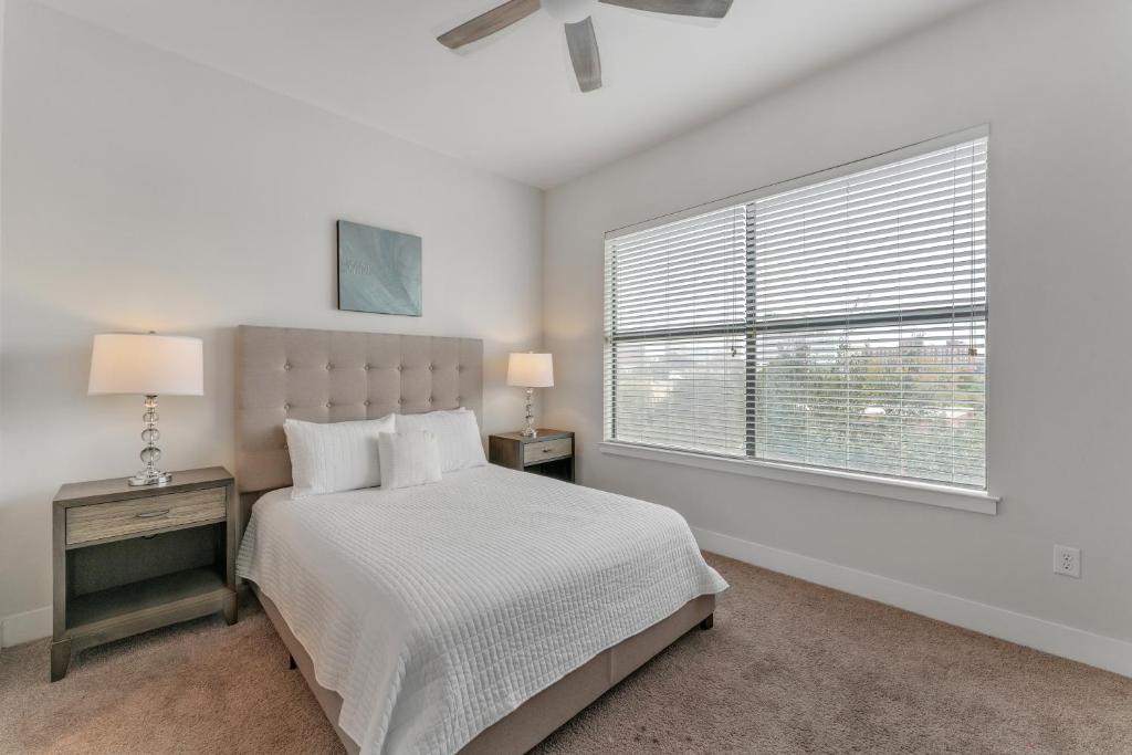 a white bedroom with a bed and a window at Elegant 2br Apartment I Pool I Gym I Parking Cs in Dallas