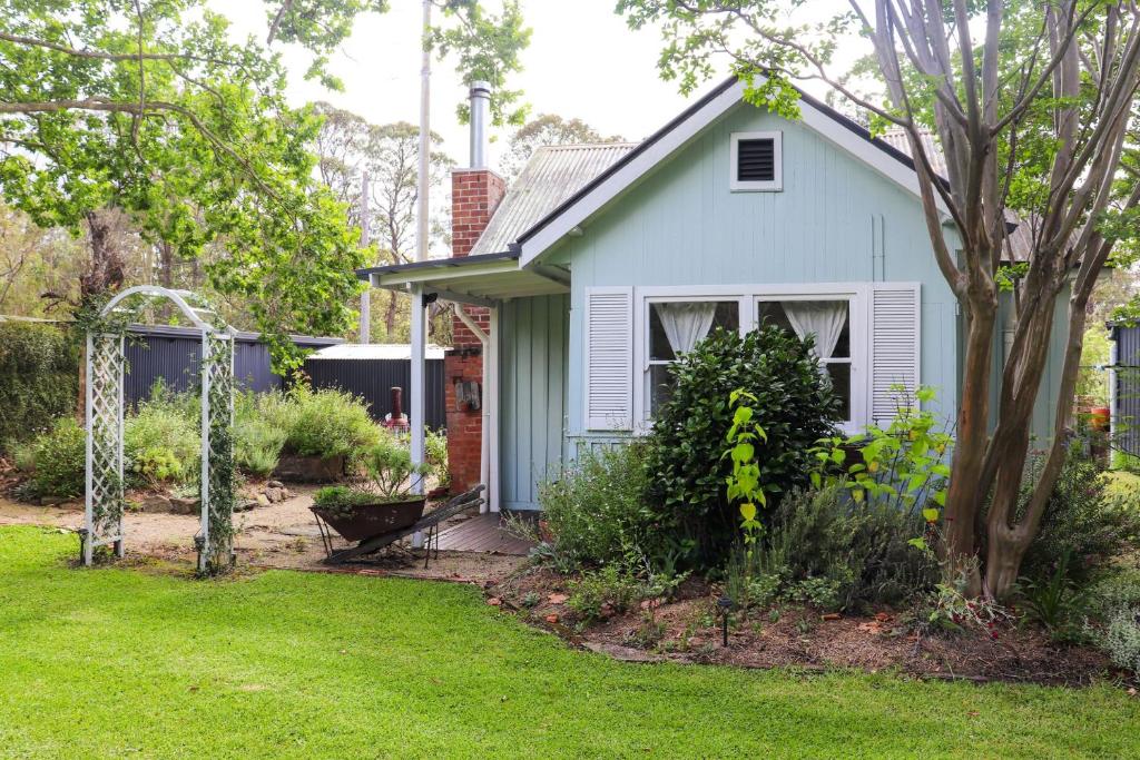 una pequeña casa blanca con patio en The Old Cottage - Country Couples Retreat en Tomerong