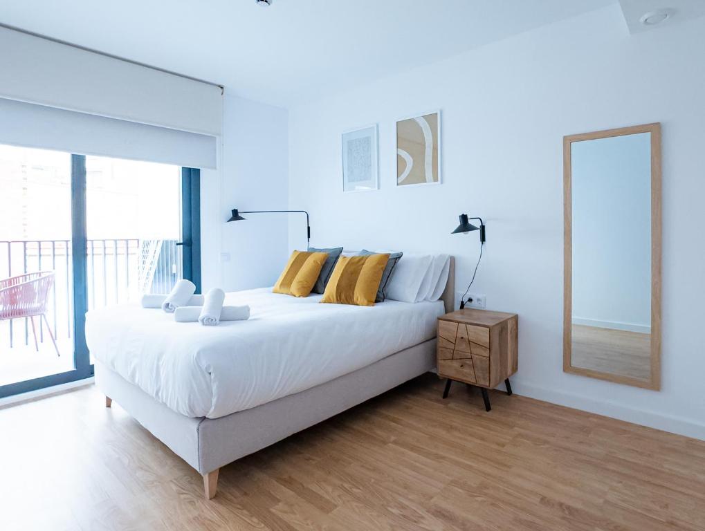 a white bedroom with a bed and a large window at Stay U-nique Apartments Albeniz BCN in Hospitalet de Llobregat