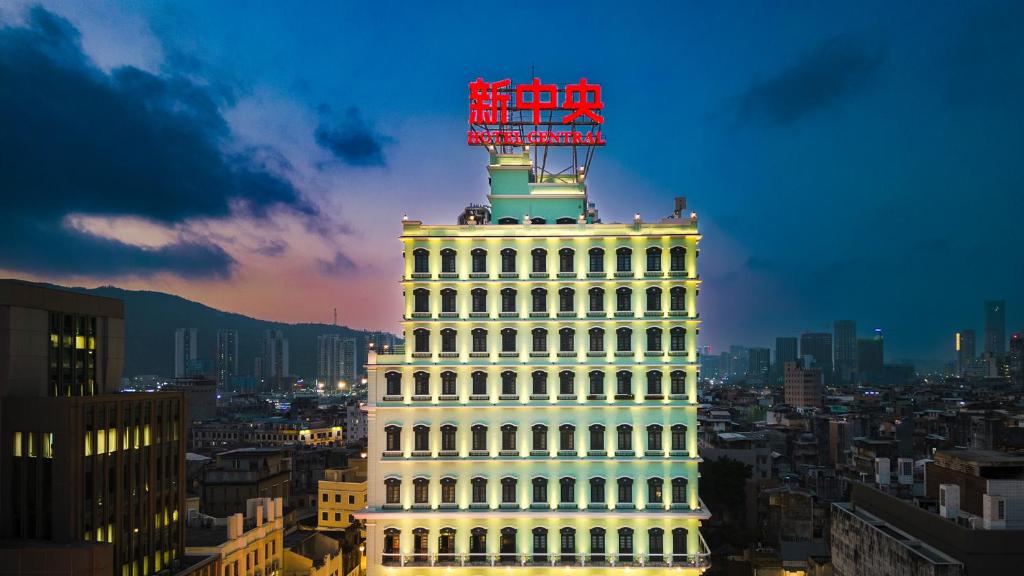 Un grand bâtiment blanc avec un panneau en haut dans l'établissement Hotel Central Macau, à Macao