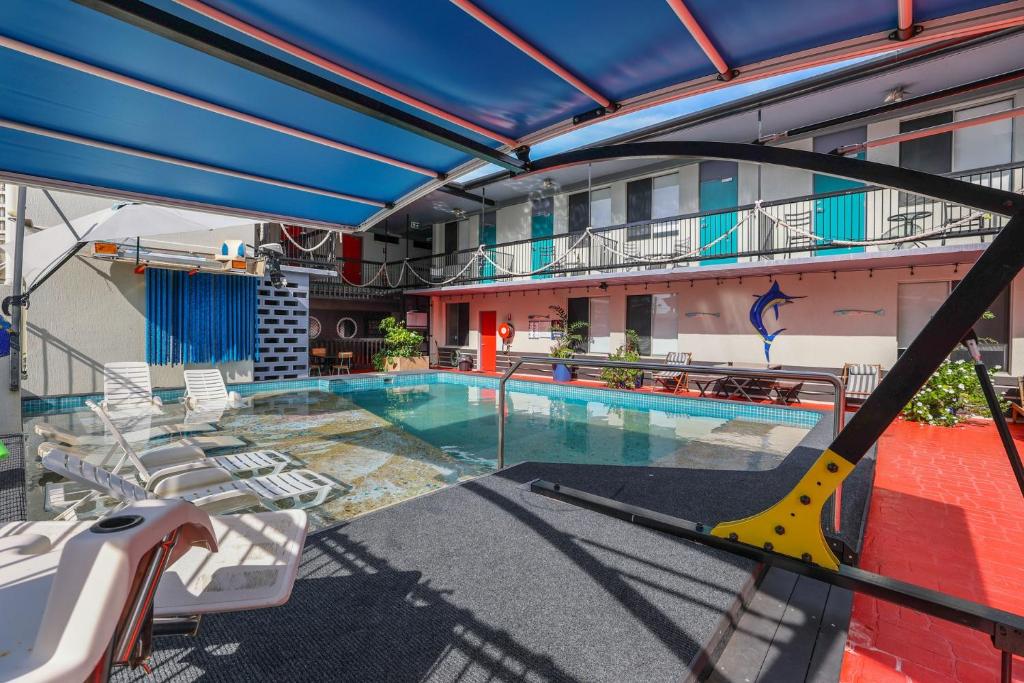 a swimming pool with chairs and a building at Capitanos in Darwin