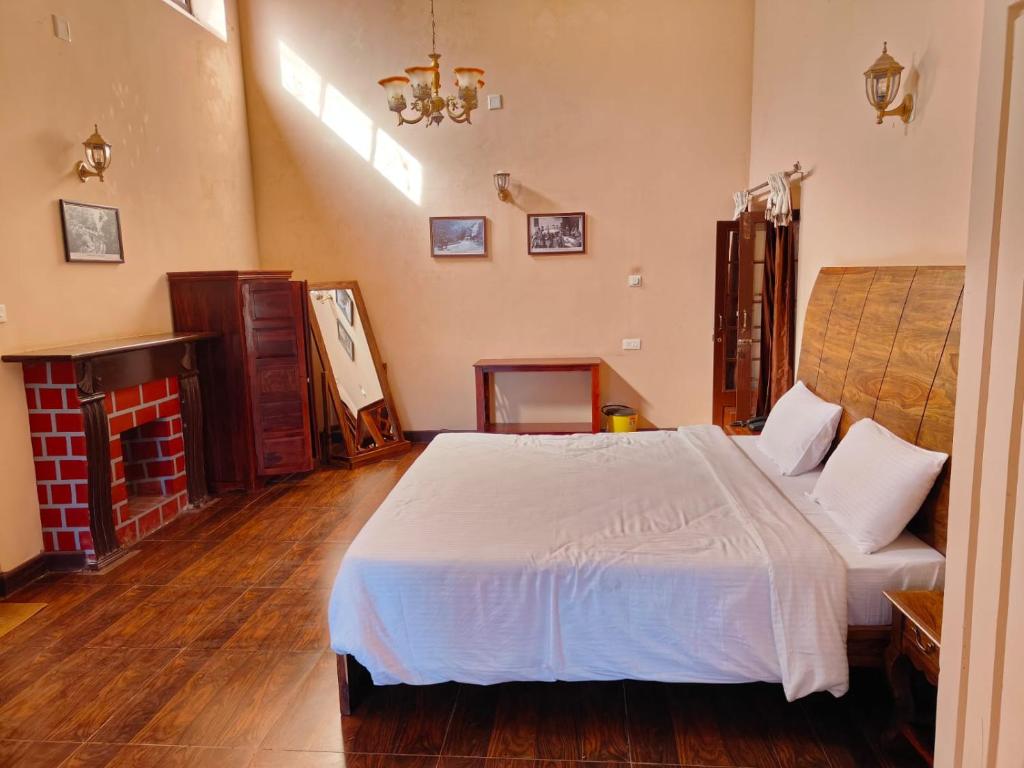 a bedroom with a white bed and a fireplace at Heritage Inn by Brown Tree Resorts in Ooty