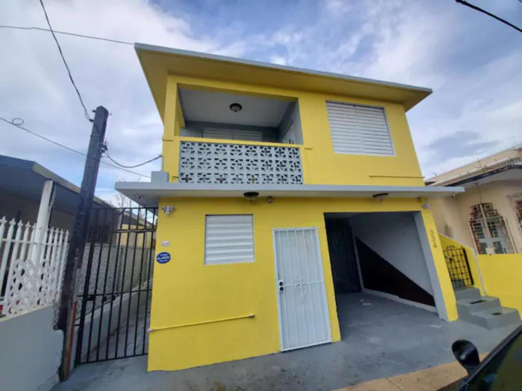 una casa amarilla con una puerta y una valla en Casa Laguna Unit 6, Spacious 3BR Near Beach and Restuarants, en San Juan
