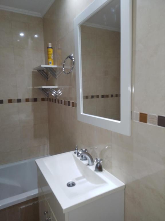 een badkamer met een witte wastafel en een spiegel bij Departamento zona céntrica balcarce in Balcarce