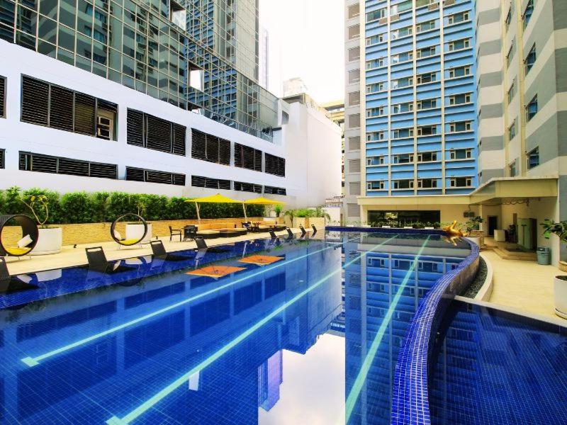 uma piscina com mesas e cadeiras num edifício em The Mini Suites Eton Tower Makati em Manila