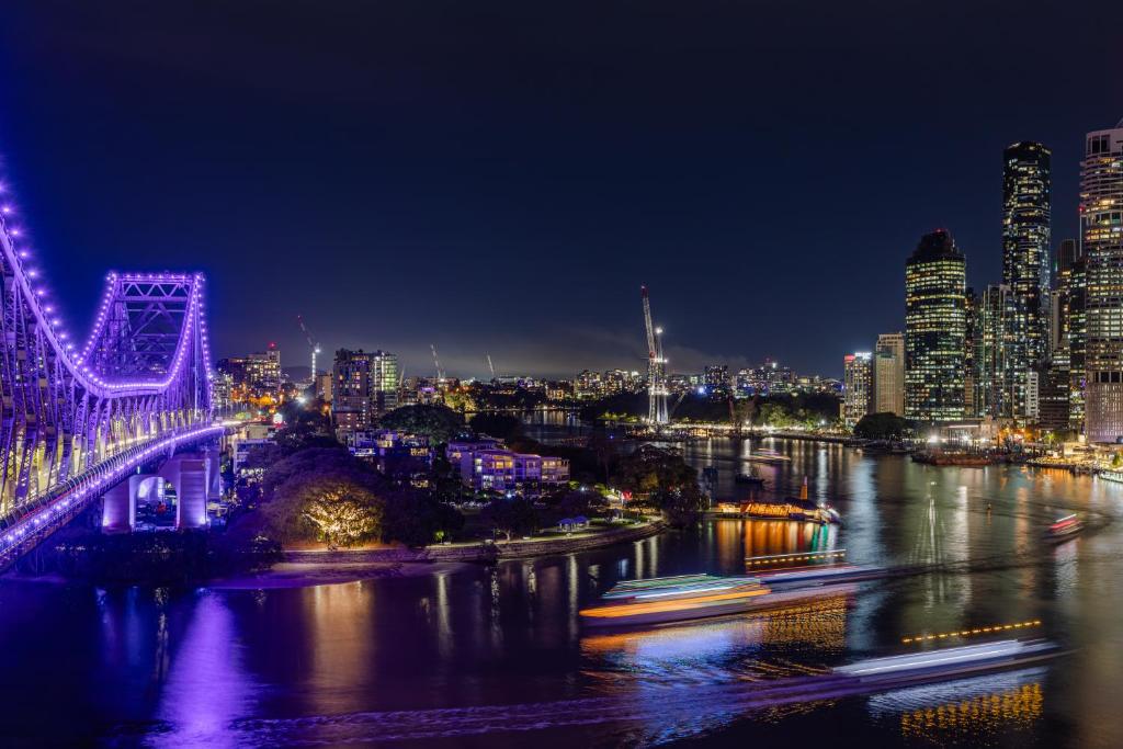 Oakbridge Hotel & Apartments Brisbane في بريزبين: اطلاله على جسر فوق نهر في الليل