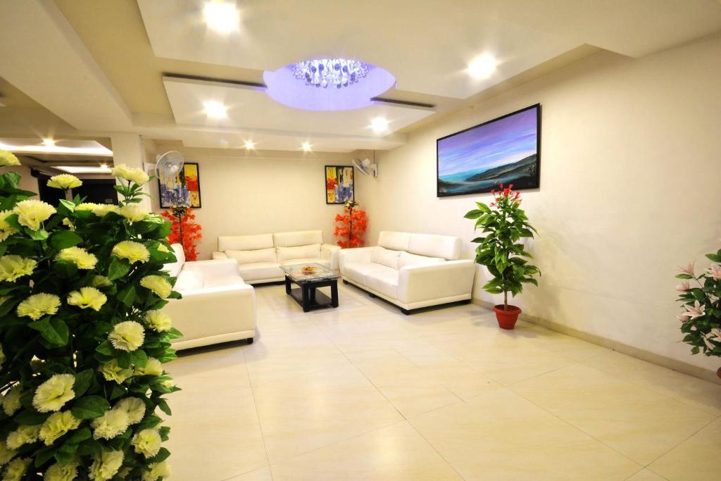 a living room with white couches and a tv at OYO Home Hotel Skyland in Ahmedabad