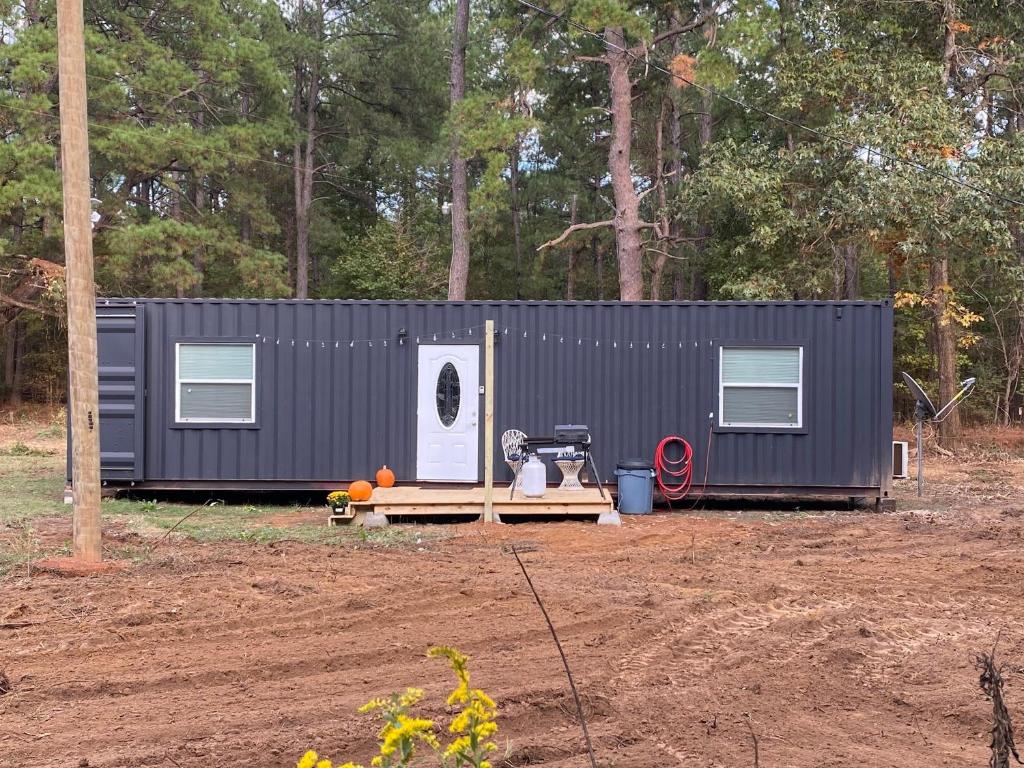 a black tiny house in front of a forest at Tiny House Oasis: Nature Escape in Nacogdoches