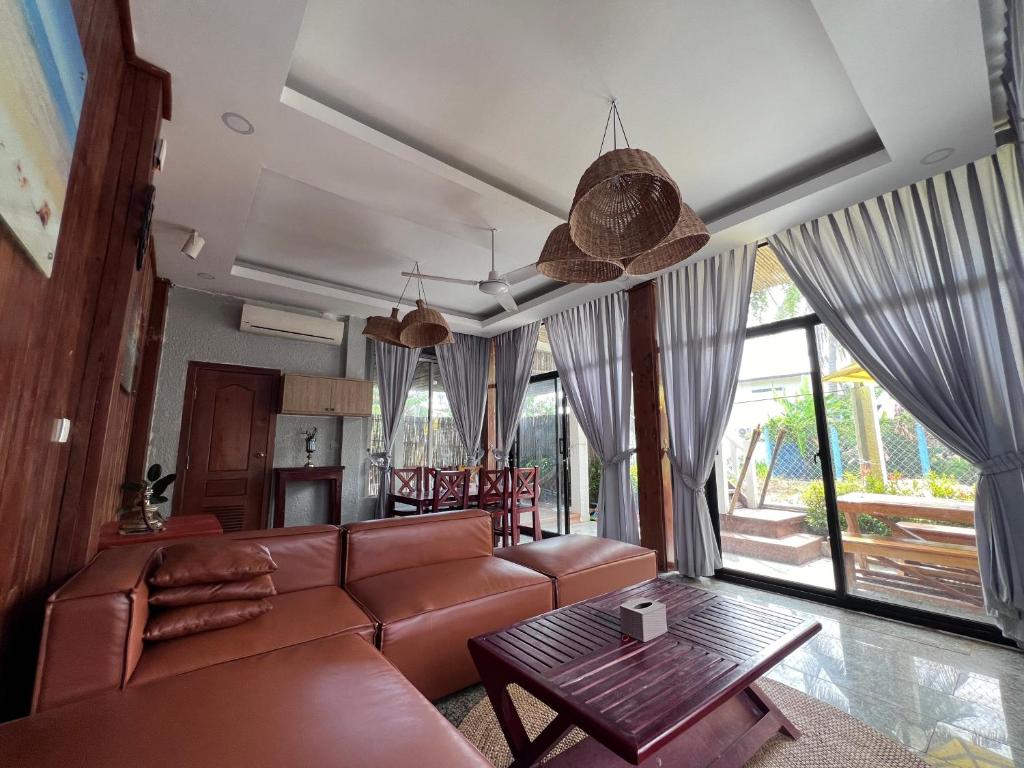 ein Wohnzimmer mit einem braunen Ledersofa und einem Tisch in der Unterkunft The White Palace Koh Sdach in Kaoh Sdach