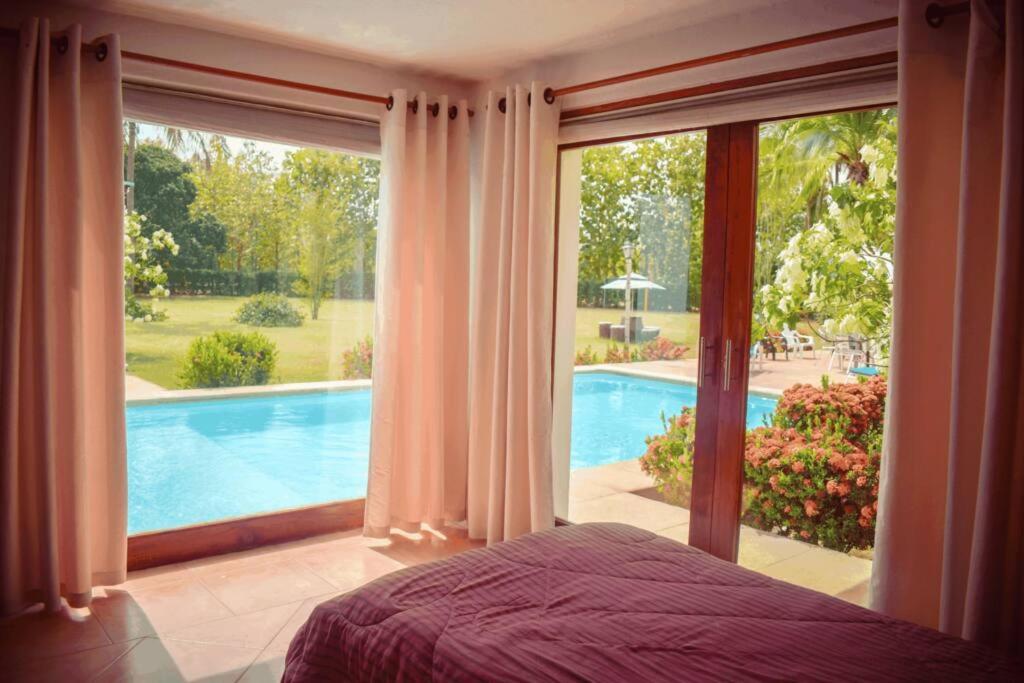 1 dormitorio con ventana grande con vistas a la piscina en Villas Mamilú, entrada y salida 100 por ciento flexible en Santa Fe de Antioquia