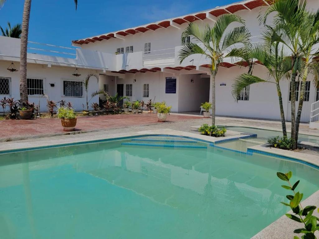 - une piscine en face d'une maison avec des palmiers dans l'établissement LA PUCCA HOTEL BOUTIQUE RESORT, à La Peñita de Jaltemba
