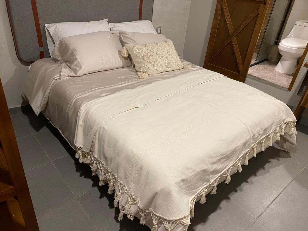 a bed with white sheets and pillows in a room at Layoo, Tu Casa en Oaxca 105 in Oaxaca City