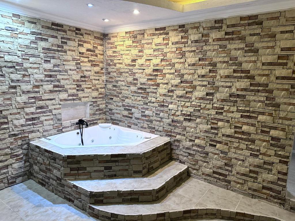 bañera en una habitación con pared de ladrillo en Killari suite en Tinogasta