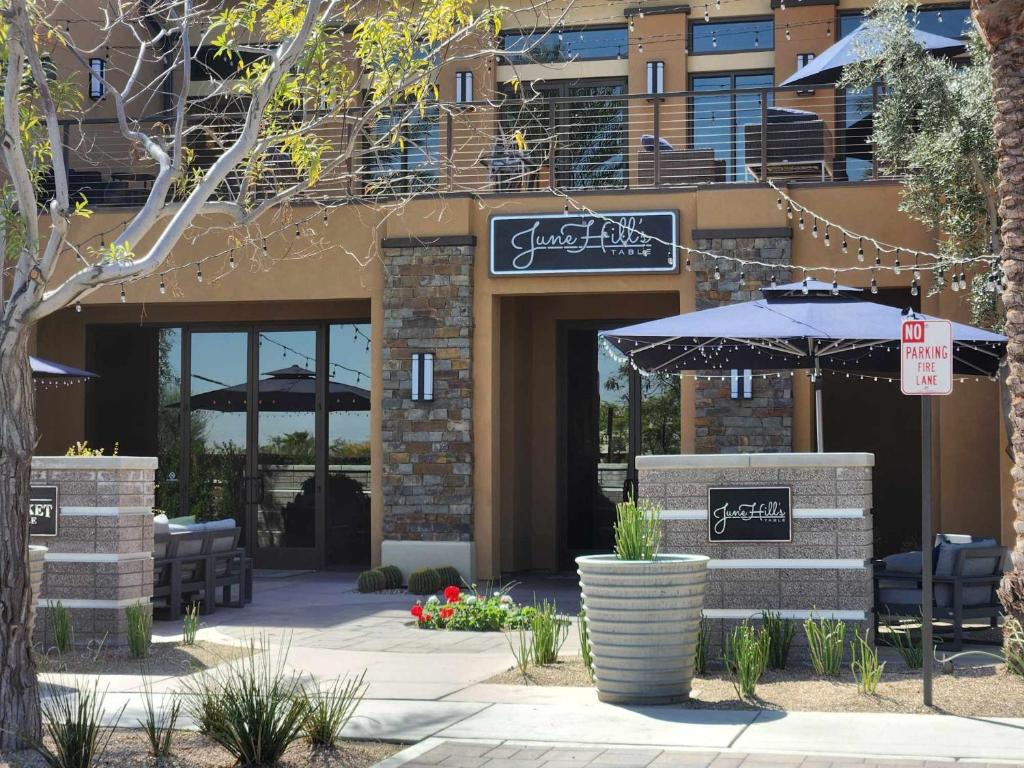 um restaurante com um guarda-chuva em frente a um edifício em Trilogy Polo Club - Casita em Indio