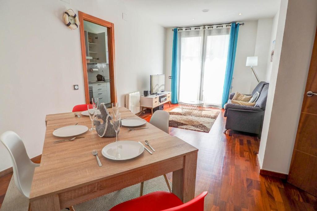 ein Wohnzimmer mit einem Holztisch und Stühlen in der Unterkunft Seaside April Apartment by Hello Homes Sitges in Sitges