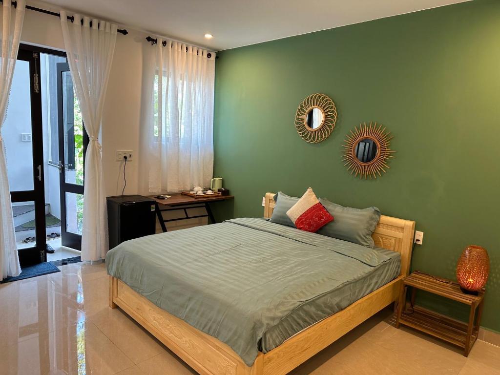 ein grünes Schlafzimmer mit einem Bett und einem Spiegel in der Unterkunft Water Palm Residence in Hiếu Nhơn