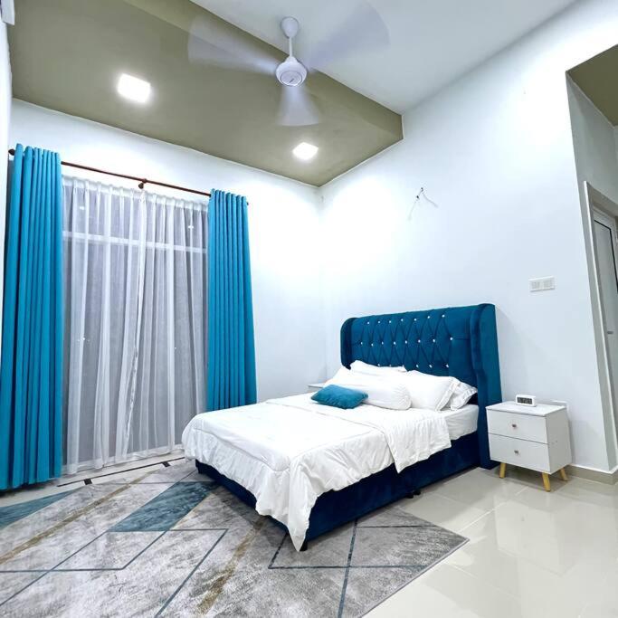um quarto com uma cama com uma cabeceira azul e uma janela em Homestay 2 Story Wakaf Che Yeh em Kota Bharu