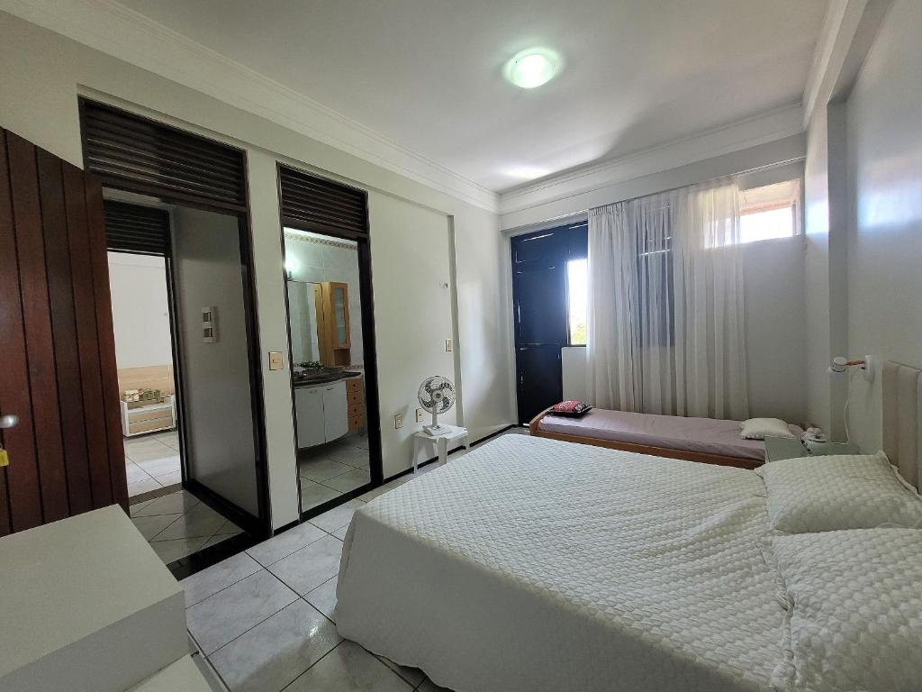 a bedroom with a large white bed and a mirror at Edifício Monte Sinai in Cabedelo