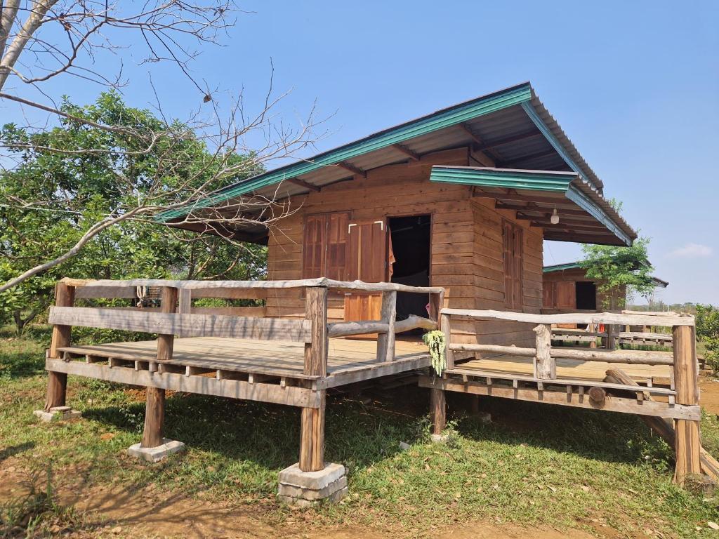 a wooden hut with two benches in front of it at Shared Happy Farm in Ban Nongboua