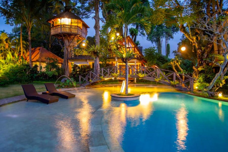 une piscine avec une cabane dans les arbres en arrière-plan dans l'établissement Green Tree House Villa Ubud, à Ubud