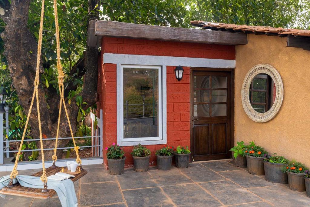 a small house with a porch with potted plants at StayVista's Tree House at Sula Wada - Cozy Home with Vintage Charm, Swimming Pool, Indoor Activities in Panchgani
