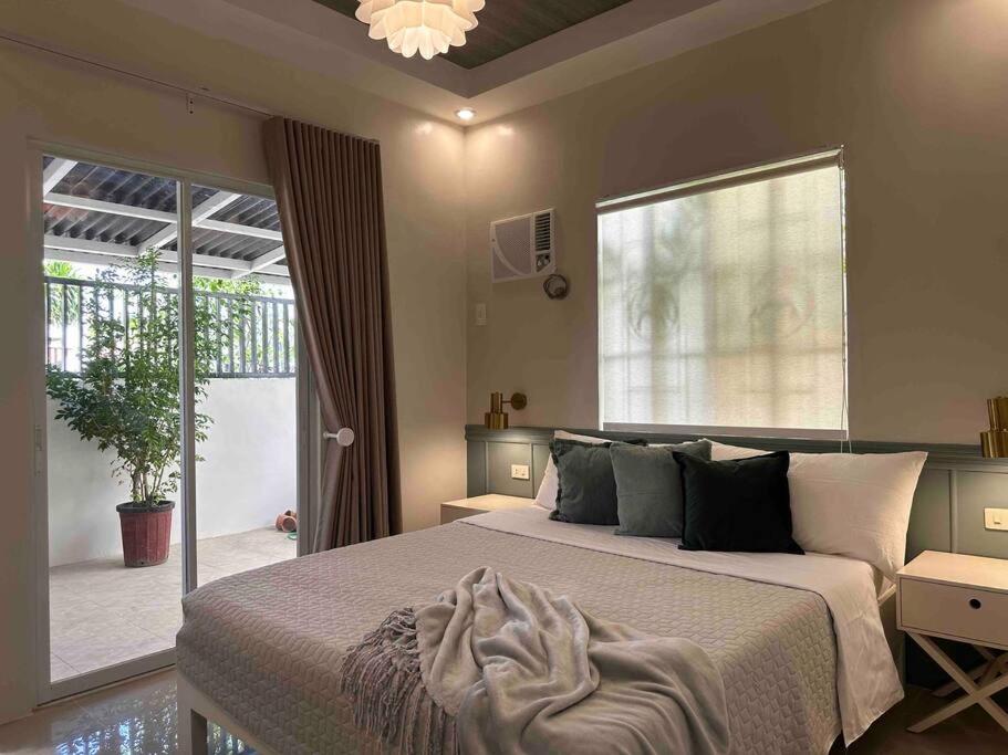 1 dormitorio con cama y ventana grande en Japandi Home A - Fully Aircon, WIFI, Hot shower, 24hGuard, Center, near Malls en General Santos