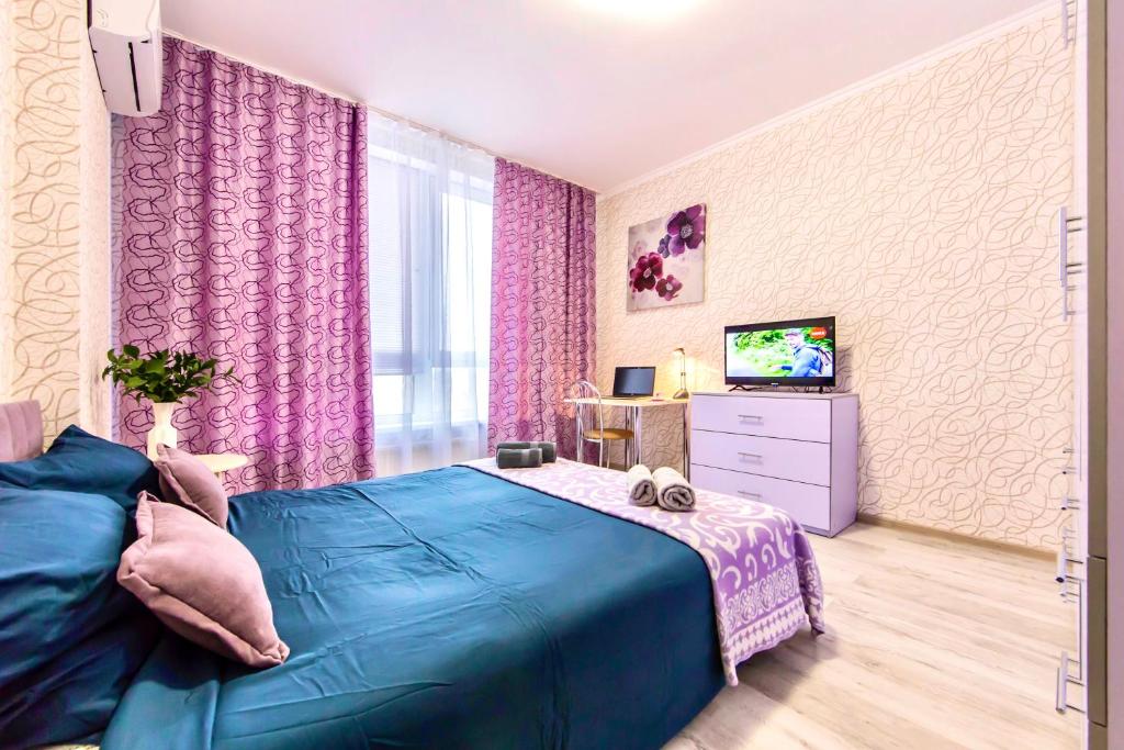 a bedroom with a blue bed and a tv at Стильные апартаменты,метро Вырлица,метро Харьковская in Kyiv