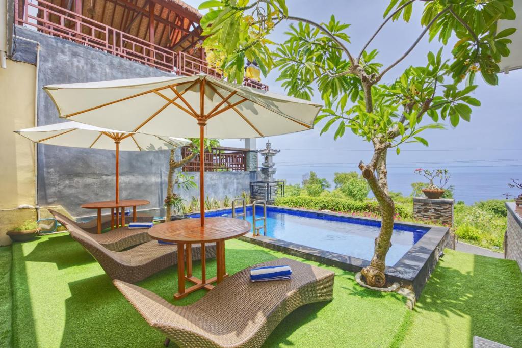 a patio with a table and chairs and an umbrella at Penida La Casa Cottage in Nusa Penida
