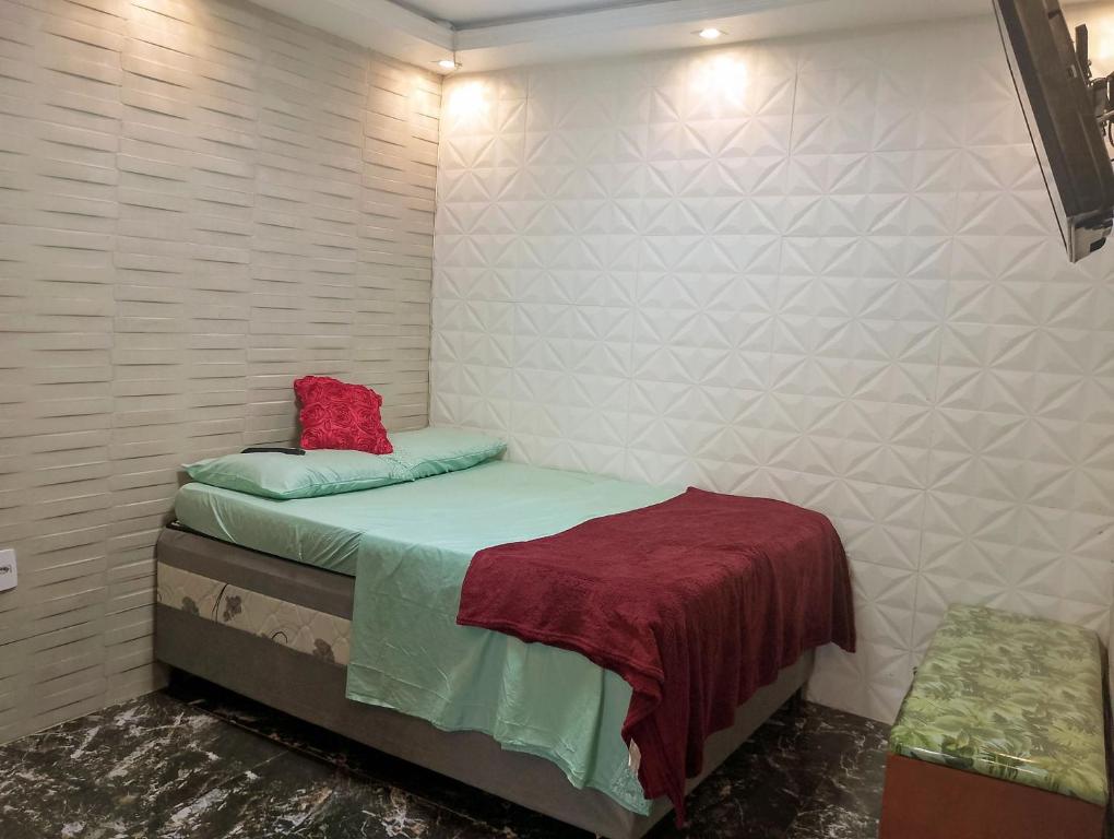 a small bedroom with a bed with a red pillow at kitnet próximo a praia in Rio de Janeiro