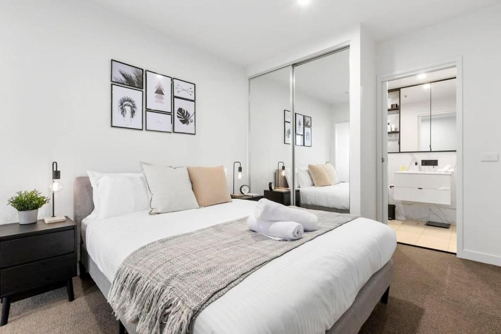 - une chambre blanche avec un grand lit et une salle de bains dans l'établissement Grandeur Apartment, à Melbourne